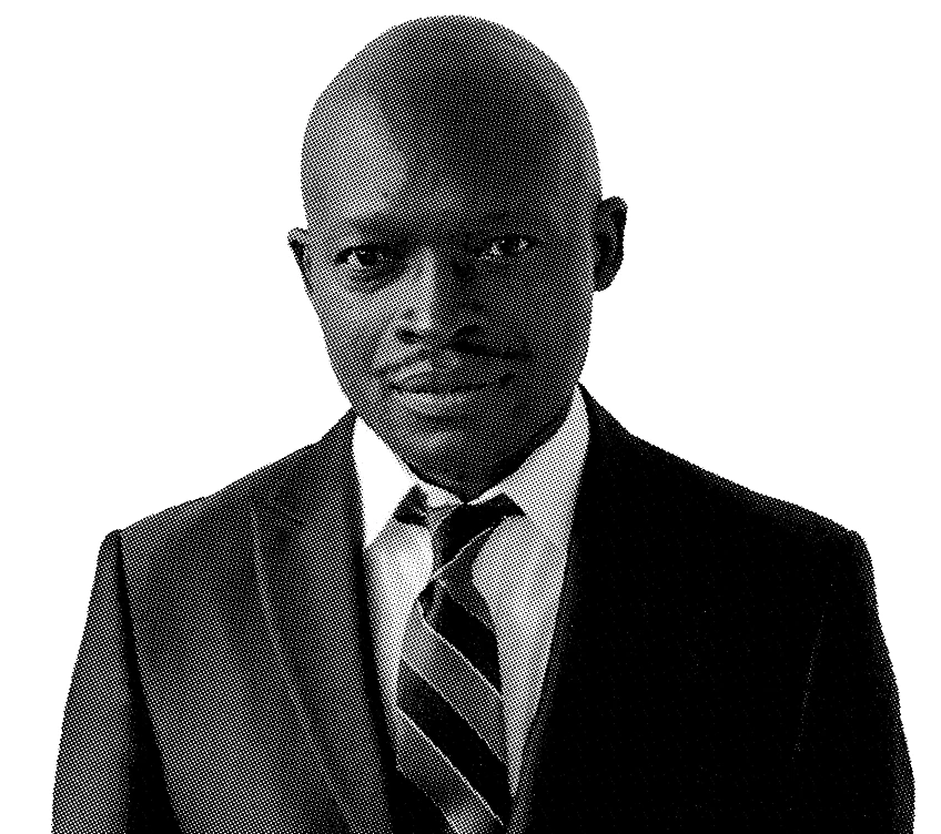 Black and white portrait of Abbey Laurel-Smith wearing a suit and tie, neutral expression.