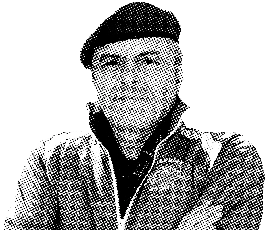 Black and white portrait of Curtis Sliwa wearing a beret and checkered jacket.