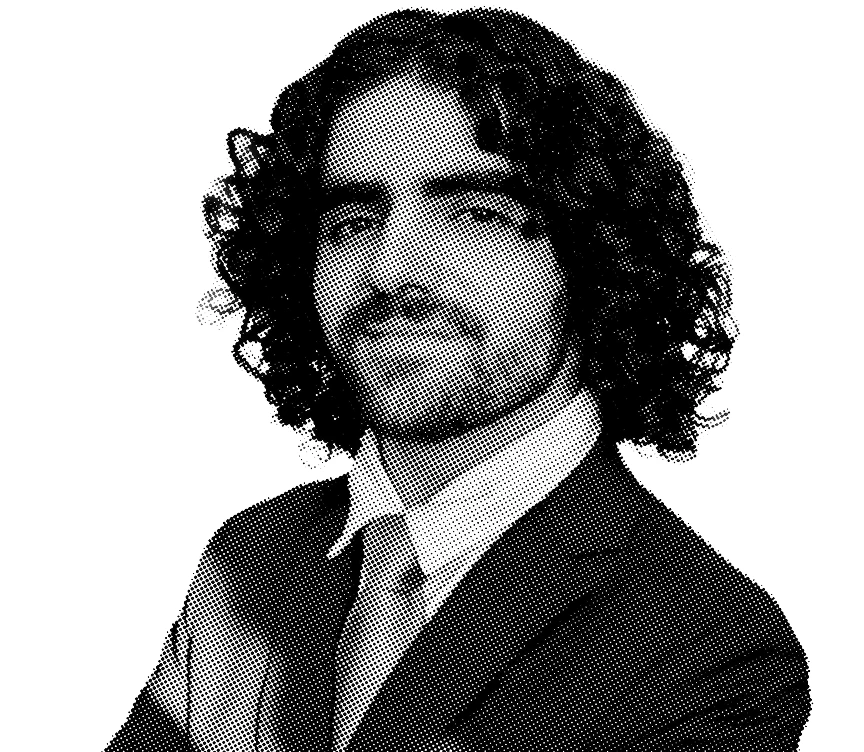 Black and white portrait of Kyle Gutierrez with long curly hair, mustache, and suit.