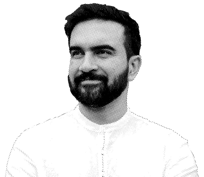 Black and white portrait of Zohran Mamdani with a beard, smiling slightly, wearing a light top.